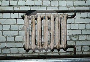 Old cast-iron battery on a brick wall background