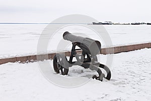 Old cast iron cannon on a winter snow-covered embankment