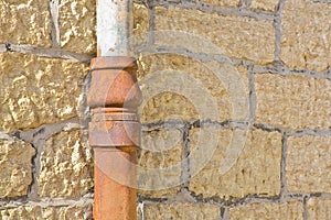 Old cast iron and copper downpipe against a stone wall