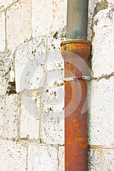 Old cast iron and copper downpipe against a stone wall - Italy