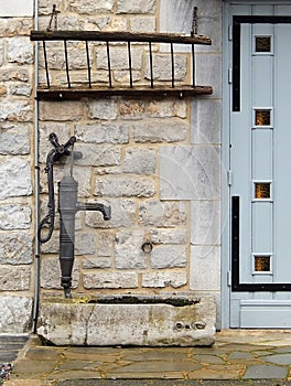 Old cast iron water pump at the door of a stone house in Han-sur-Lesse (Belgium)