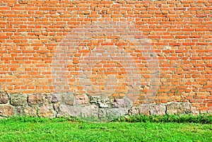 Old castle brick wall with green grass at the bottom