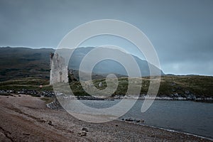 A old castle on the shore mountain lake with rain clouds