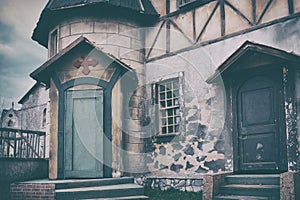 Old Catholic Church with a cross over the door. The architecture of the European middle ages in dark colors. Cloudy sky in the