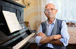 Old compositor sitting beside piano photo