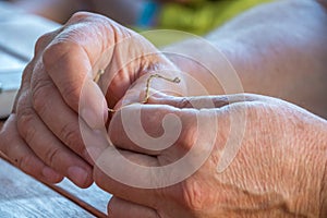 Old caucasian hands bending copper wire