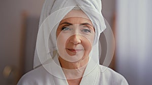 Old Caucasian middle-aged woman mature lady elderly model female with towel on head in bathrobe looking at camera