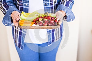 Old caucasian woman senior caucasian in casual jeans clothes offer some fresu seasonal fruits to you. melon, orange and cherry for