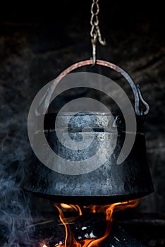 An old cauldron cooking food on a mountain with an open flame