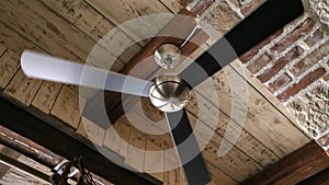 Old ceiling fan lamp spinning in the antique interior with brick walls and wooden roof