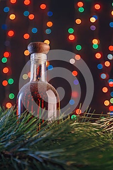 Old cellar dusty bottle of brandy, scotch, whiskey, cognac on blurry Christmas garland lights bokeh background, green pine