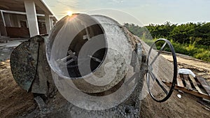 an old cement mixer machine by the pile of sand at the construction site.