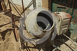 Old cement mixer and sand in a construction site