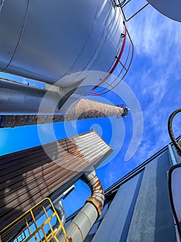 An old ceramic chimney and an old and new flue gas dust collector behind a coal boiler, a grate, against the blue sky