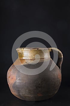 old ceramic jug, with some damage, photographed on a black background