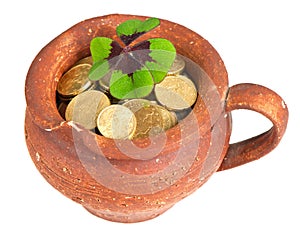 Old ceramic pot with money coins and clover leaf