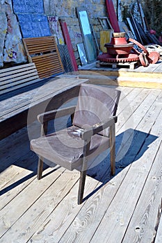 Old chair covered in artificial leather on a wooden deck