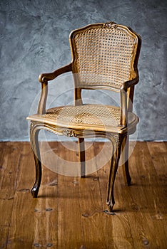 Old chair on a gray wall background.