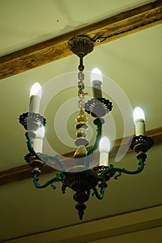 Old chandelier with five lamps hangs on the ceiling with a pre-revolutionary house.