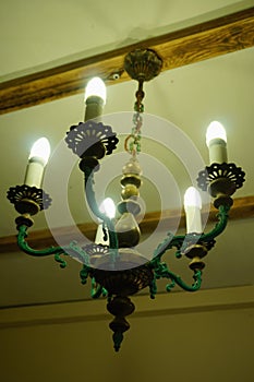Old chandelier with five lamps hangs on the ceiling with a pre-revolutionary house.