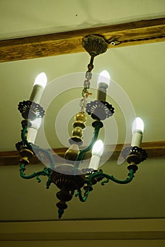 Old chandelier with five lamps hangs on the ceiling with a pre-revolutionary house.