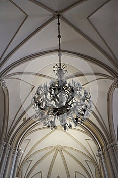 An old chandelier with glass - hangs from a ceiling