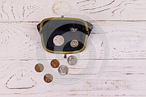 Old change purse with several coins on white wooden background. Concept of poverty or bankruptcy