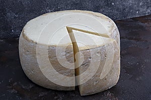 Old cheddar cheese. Wheel aged cheese. Aged cheddar cheese wheel on dark wooden floor