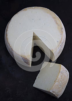 Old cheddar cheese. Wheel aged cheese. Aged cheddar cheese wheel on dark wooden floor