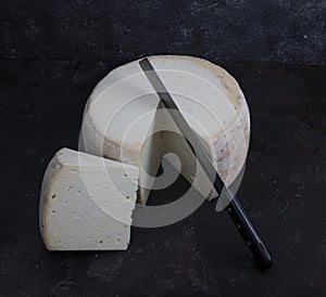 Old cheddar cheese. Wheel aged cheese. Aged cheddar cheese wheel on dark wooden floor