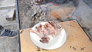 Old chef breaks ribs in his fingers and checks the cooked meat on a white plate. Tasting during the preparation of food