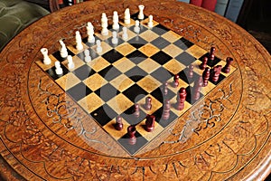 An old chess set on a purpose build carved chess board and table in an English country house