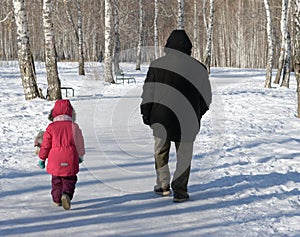 Old and child walking in winter park