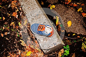 Old children`s sneaker near the gutter.