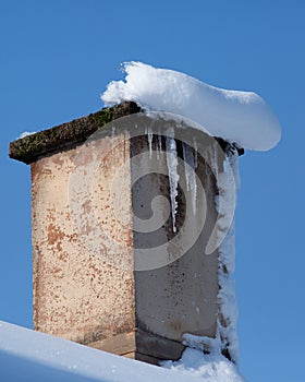 Old chimney covered with snow and icicled