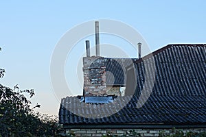 Old chimney on a gray slate roof of a rural house