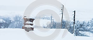 Old chimney made of red brick and a TV antennas on a rural roof. Everything is covered in snow. Winter landscape