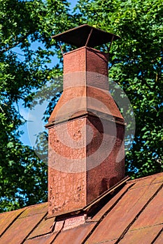 Old chimney on a retro style red tin roof.