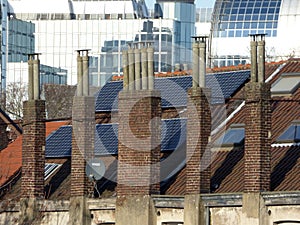 Old chimneys and modern solar panels on house`s roof