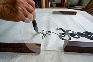 An old Chinese calligrapher is writing brush characters, creating Chinese calligraphy works.