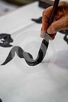 An old Chinese calligrapher is writing brush characters, creating Chinese calligraphy works.