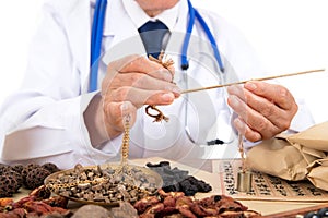 An old Chinese doctor is preparing herbs in front of a white background