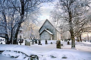 Old Church and graveyard covered in snow, lit by the predawn light
