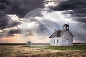 An old church on the prairie under a stormy sky