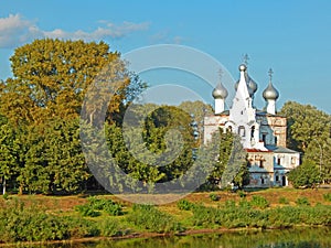 An old church standing on the river bank surrounded by trees