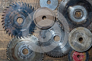 Old circular saw blades and emery wheels on wooden table, closeup, top view. Carpentry tools, sawing and grinding equipment