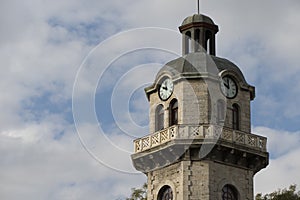 Old city clock tower on a cloudy sky background