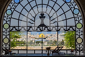 The Old City of Jerusalem and the Dome of the Rock, seen with the silhouette of a cross in the window of Dominus Flevit chapel,