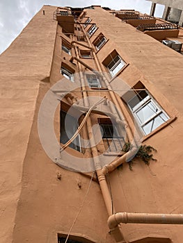 Old civilian building exterior wall rustic painting, window irons, water pipes, electric cables