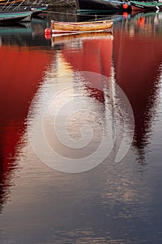 Old classic brown color varnished fishing boat in a river. Old boat with red sail reflection in water. Galway city, Ireland. Fine